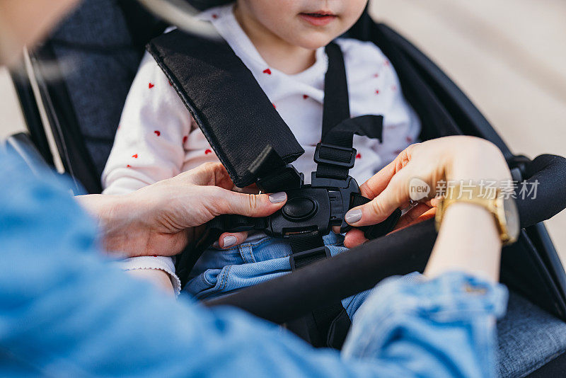 一位匿名妇女正在为Childrenâ的婴儿车调整皮带